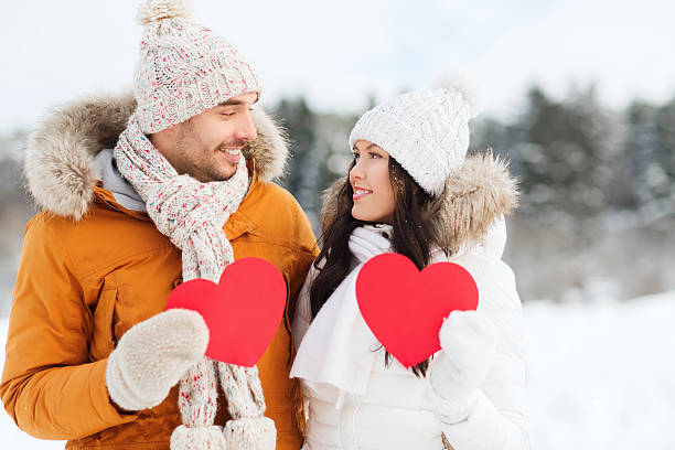 istock happy couple with red hearts over winter landscape 607966302