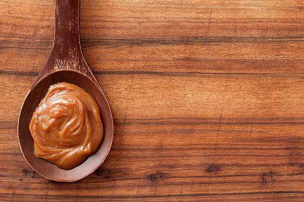 milk caramel Top view of wooden spoon over table with dulce de leech on it dulce de leche stock pictures, royalty-free photos & images