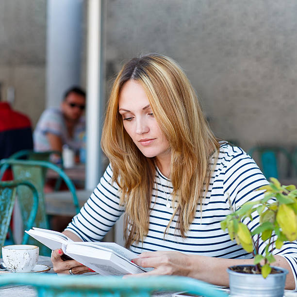 istock Woman drinking coffee and reading book in cafe 607970620