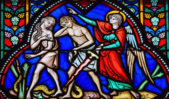 Brussels, Belgium - July 26, 2012: Adam and Eve expelled from the Garden of Eden on a stained glass window in the cathedral of Brussels, Belgium.