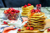 Pancakes with fresh strawberry and jam on white wooden background