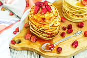 Pancakes with fresh strawberry and jam on white wooden table