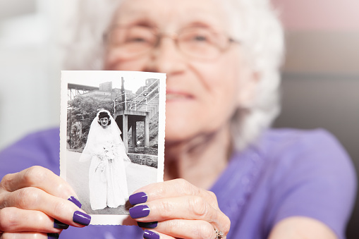 An 89 year old woman holding a photo of herself as a young bride.