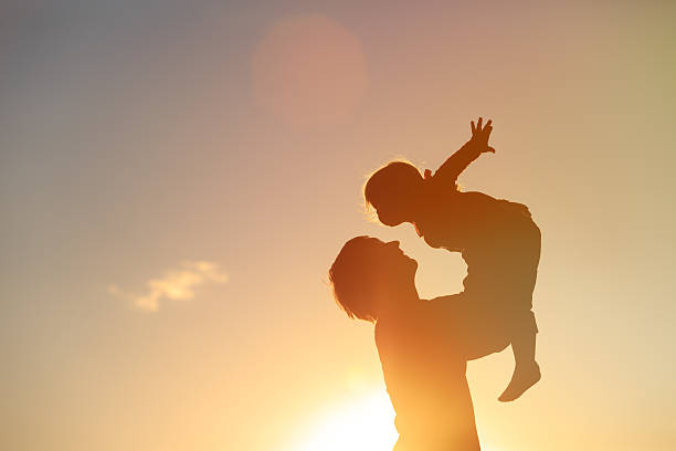 istock Father and little daughter silhouettes play at sunset 607990844