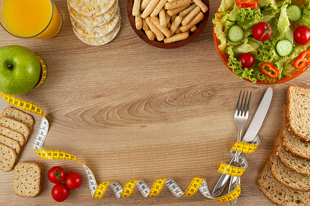 gesunde lebensmittel auf holz küchentisch - healthy eating fork tape measure still life stock-fotos und bilder