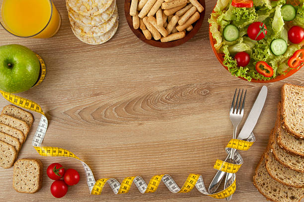 alimentos saudáveis na mesa de cozinha de madeira - healthy eating fork tape measure still life - fotografias e filmes do acervo