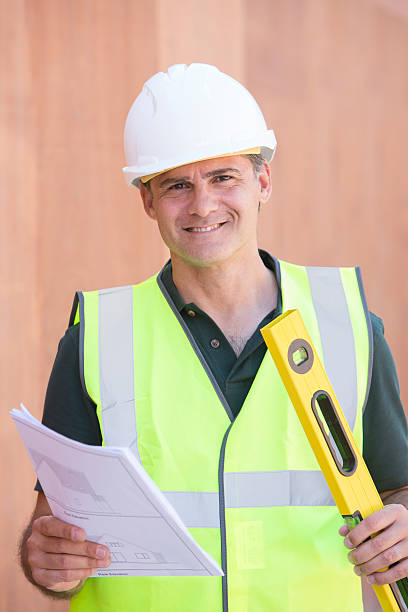 Portrait Of Construction Worker On Building Site With House Plan Portrait Of Construction Worker On Building Site With House Plans basement construction site construction blueprint stock pictures, royalty-free photos & images