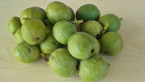 istock Immature green shelled walnuts fruits on table 608000454