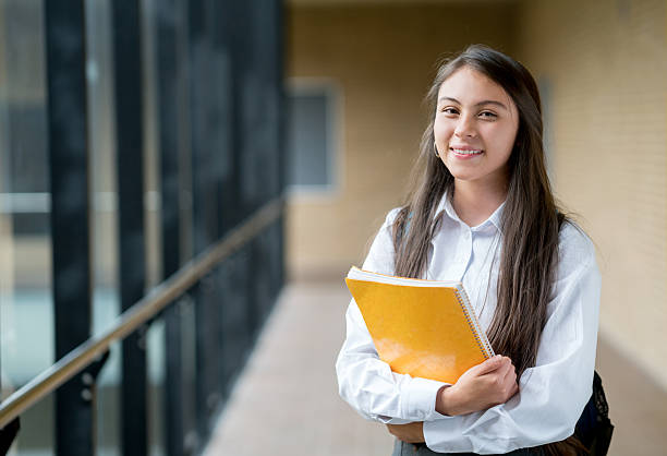 Happy student at the school Happy female student looking at the camera smiling and holding a notebook - education concepts high school student stock pictures, royalty-free photos & images