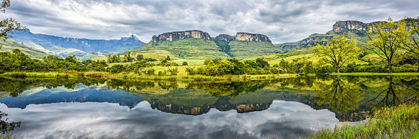 panorama of flat-top mountains and green hills reflected in water flat top mountains and green lush hills reflected in water on cloudy day, panorama. zululand stock pictures, royalty-free photos & images