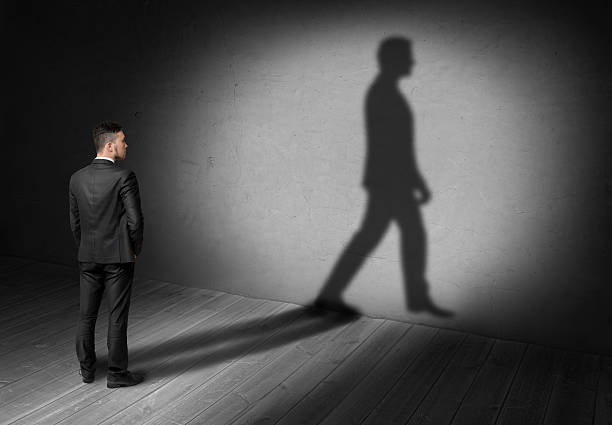 istock Back view of a businessman looking at his walking shadow 608004530