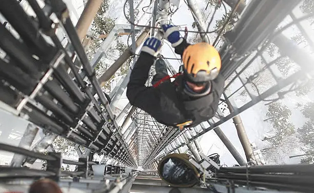 Telecommunication manual high worker engineer repairing 260 feet tall mobile base station (communication tower), high angle of view. 