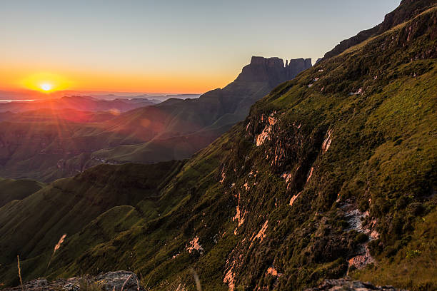 morning rays hitting cliffs in red and orange color morning rays of the rising sun hit the cliffs in red and orange color, with the deep valley below drakensberg mountain range stock pictures, royalty-free photos & images