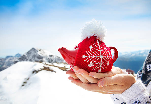 istock Knotted cap tea pot in the hands 608008176