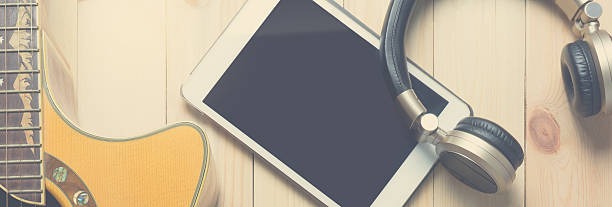 Acoustic Guitar with headphone and tablet for music practicing and music writing.