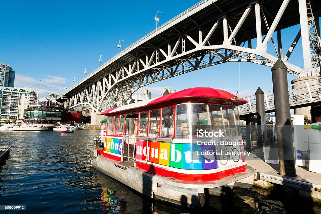 Aquabus Ferry in False Creek Bay Granville Island Vancouver Canada Vancouver, Canada - July 10, 2016: On a sunny day while there are no passengers, a small Aquabus ferry boat is docked along the water in False Creek Bay alongside the Granville street bridge.  Granville Island Stock Photo