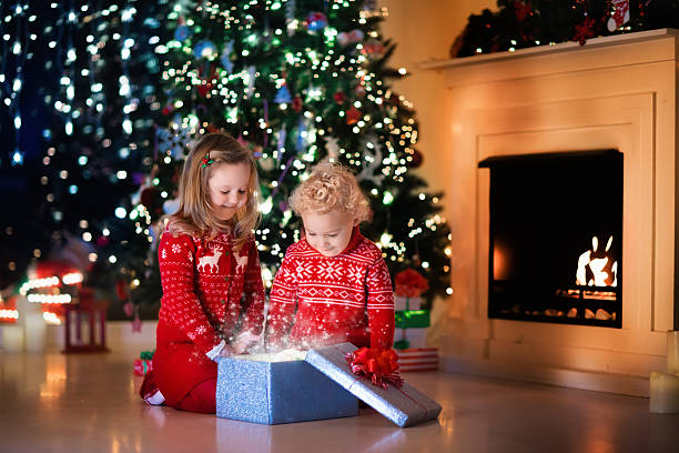 istock Kids opening Christmas presents at fireplace 608488430