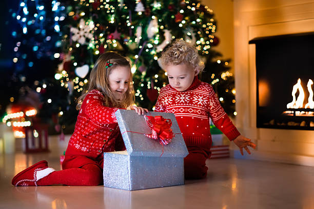 istock Little kids opening Christmas presents at fireplace 608493544