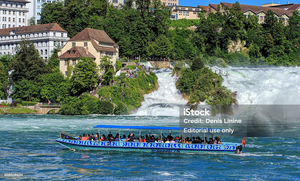 Boat at the Rhine Falls in Switzerland Neuhausen am Rheinfall, Switzerland - 22 June, 2016: people in a boat on the the Rhine river, just below the Rhine Falls. The Rhine Falls is the largest plain waterfall in Europe, located on the Rhine river in Switzerland on the border between Swiss cantons of Schaffhausen and Zurich.  Building Exterior Stock Photo