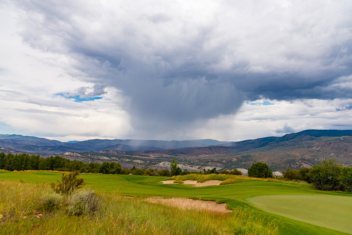 Playing Red Sky Ranch mountain golf course in Colorado a passing storm cloud rained in the distance.