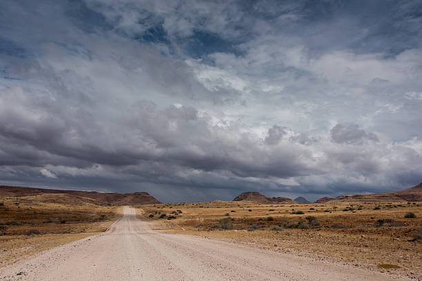 istock Rural dirt road leading nowhere with dark stormy clouds above. 608515716