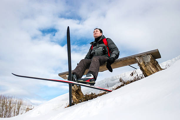istock Skier hiker relaxing on bench during winter forest skiing 608516358
