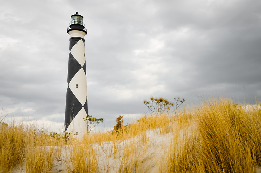 Cape Lookout lighthouse surrounded by the grass and sand on the island 