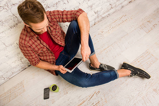 istock Top view of young man siting on floor with tablet 608538066