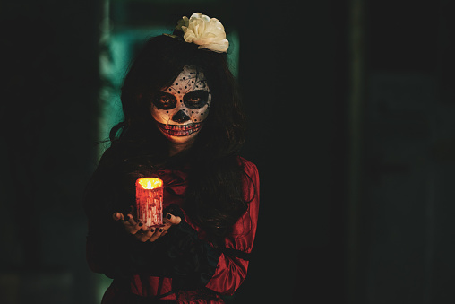 Halloween girl holding glowing candle in dark house