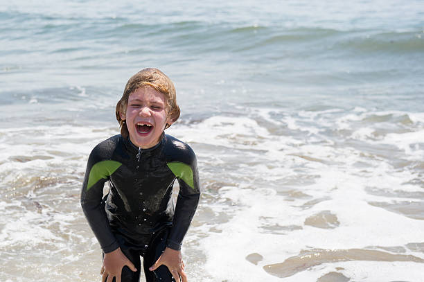 Laughing child with a lost tooth plays in the ocean