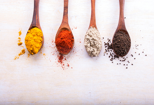 Various Spices In Wooden Spoons On Old White Wooden Table