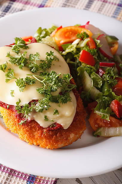 istock Chicken Parmigiana and vegetable salad closeup. vertical 608573570