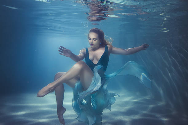 Woman dives underwater. Woman in a dress dives underwater, she dances on the bottom. levitation photos stock pictures, royalty-free photos & images