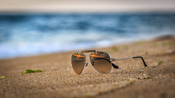 istock Sunglasses on the beach with sunrise reflections 608578510