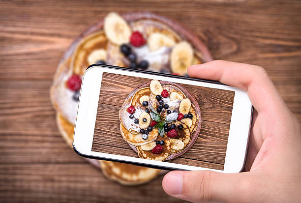 istock Hands taking photo pancakes with fresh fruit with smartphone. 608584850