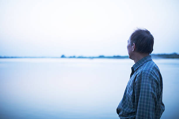 istock old man standing infront of river 608594198