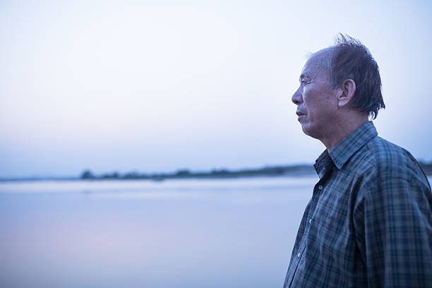 istock old man standing infront of river 608594406