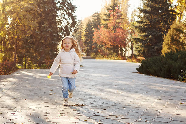istock Little girl running in autumn park. 608610936