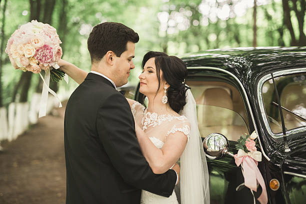 istock Beautiful wedding couple posing near splendid retro car 608620950