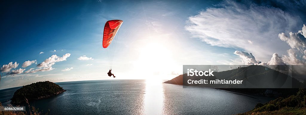 Paraglider flying over the water Paraglider flying over the water during sunset with the mountains Paragliding Stock Photo