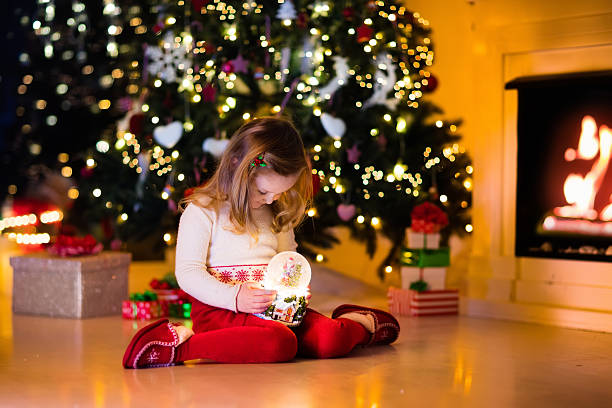 istock Little girl holding snow globe under Christmas tree 608634038