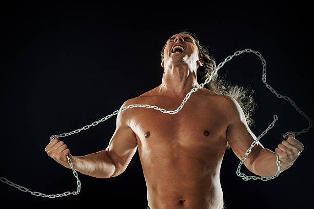 istock Young man with long hair breaks the iron chain. Strong 608634266
