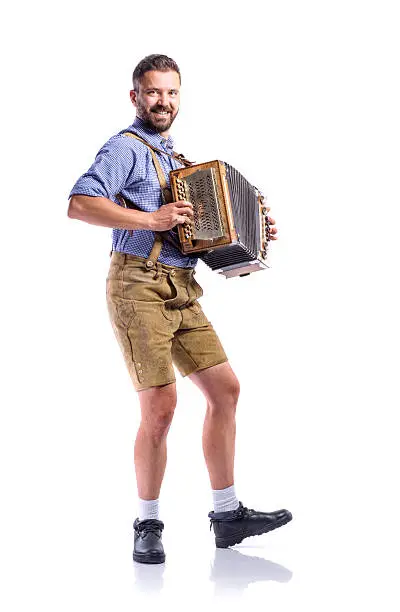 Handsome young man in traditional bavarian clothes playing accordion. Beer Fest. Studio shot on white background, isolated.