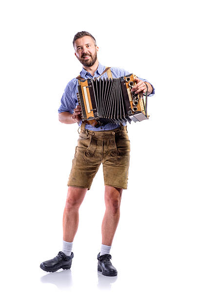 Man in traditional bavarian clothes playing accordion. Beer Fest Handsome young man in traditional bavarian clothes playing accordion. Beer Fest. Studio shot on white background, isolated. Lederhosen stock pictures, royalty-free photos & images