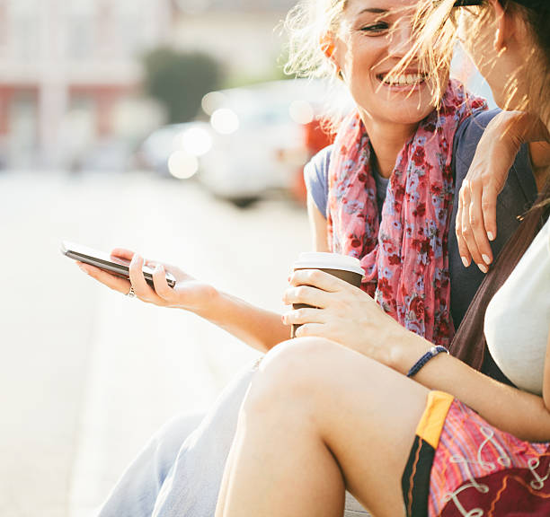 istock Happy female friends reading a text message outdoors 608639414