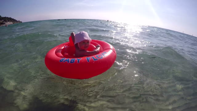 baby girl in swimming tube - swimming , relaxing , sunbathing - first time in sea water