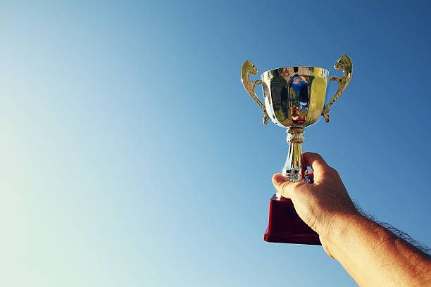 istock Man holding up a trophy cup as a winner 609032740
