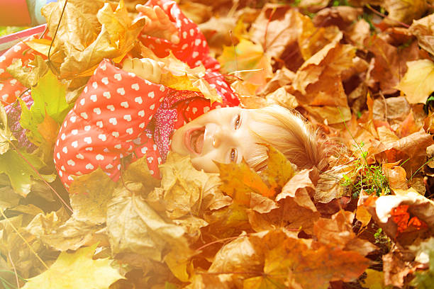 istock cute little girl playing with autumn fall leaves 609032950