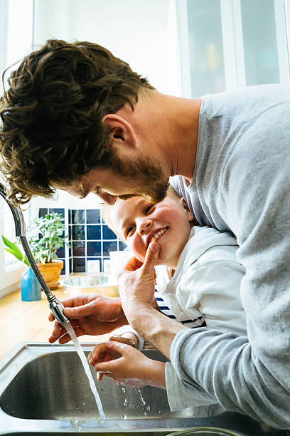 istock Father Washing Sons Hands In Kitchen Sink After Cooking Together 609033178