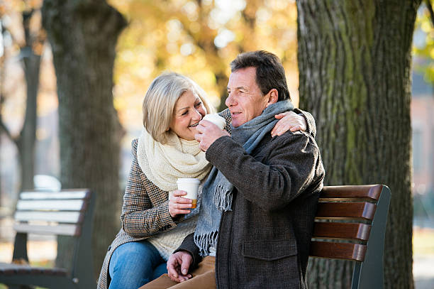 istock Senior couple sitting on bench, drinking coffee. Autumn nature. 609033554